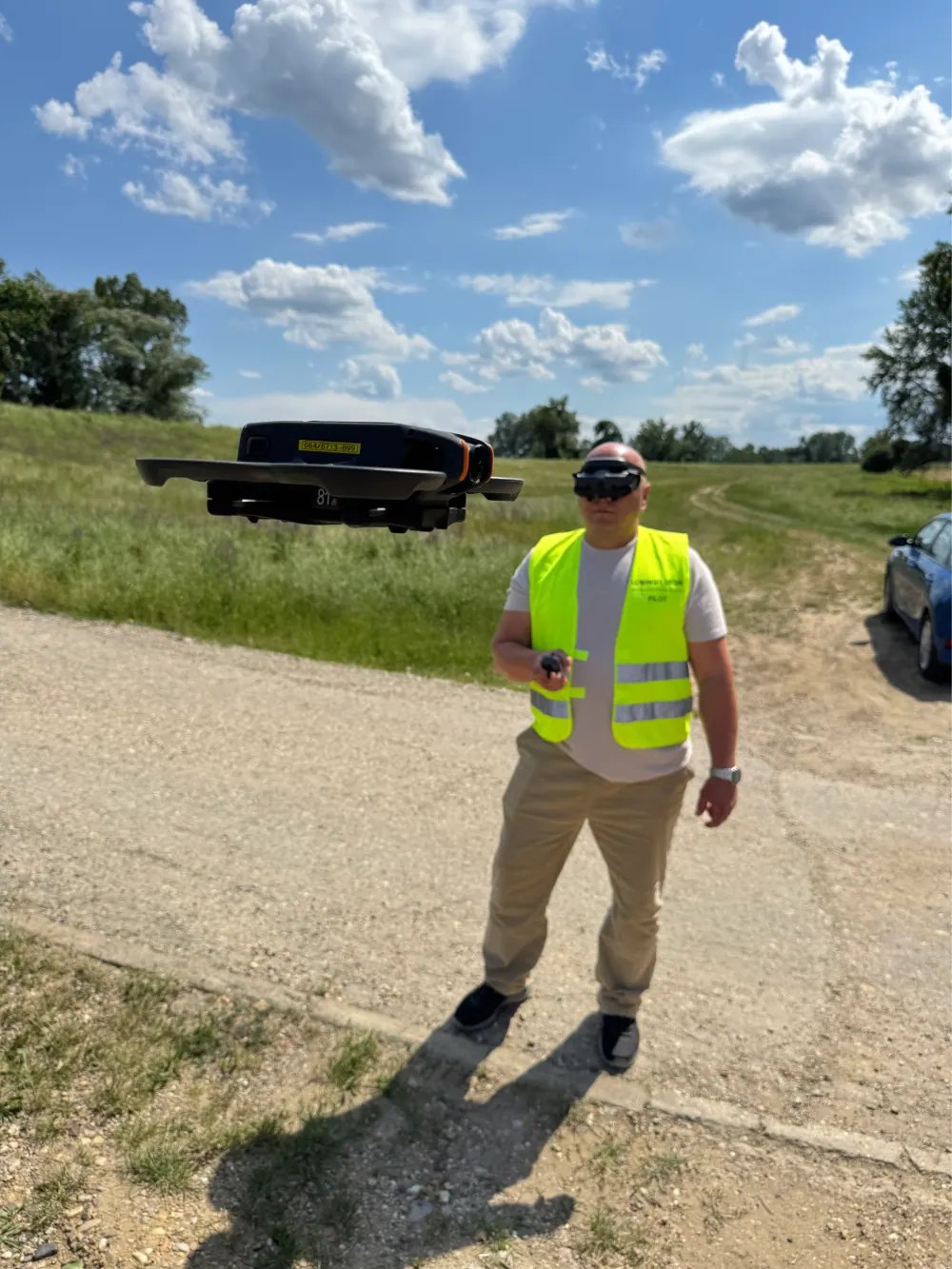 Pilot u prsluku Lomingo upravlja većim dronom na terenu