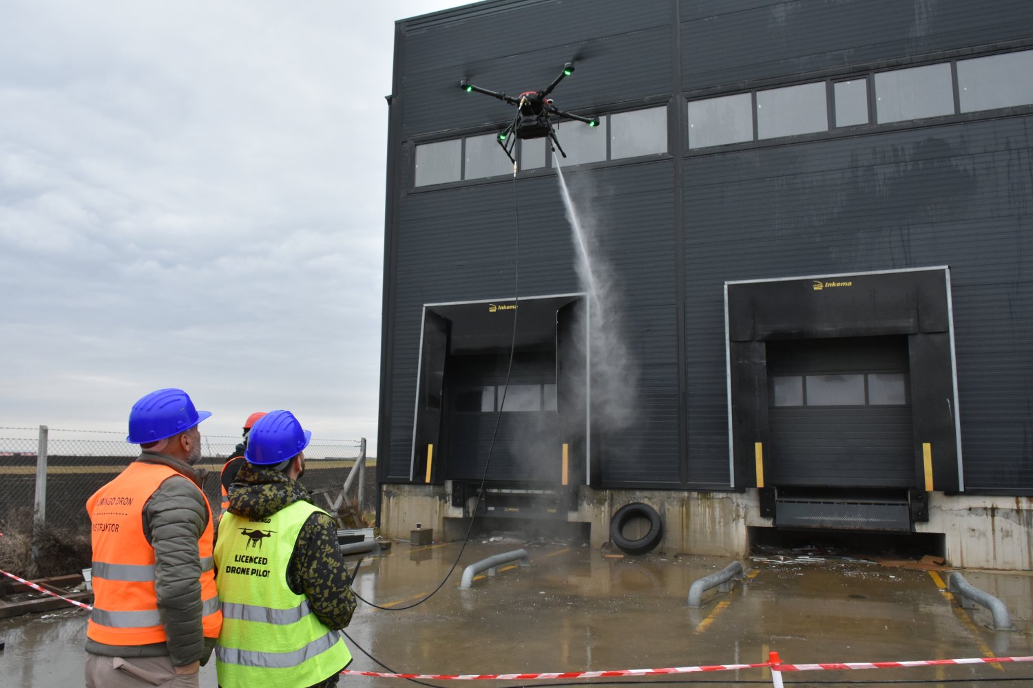 Dron pere tamnu fasadu poslovnog objekta dok polaznici prate rad
